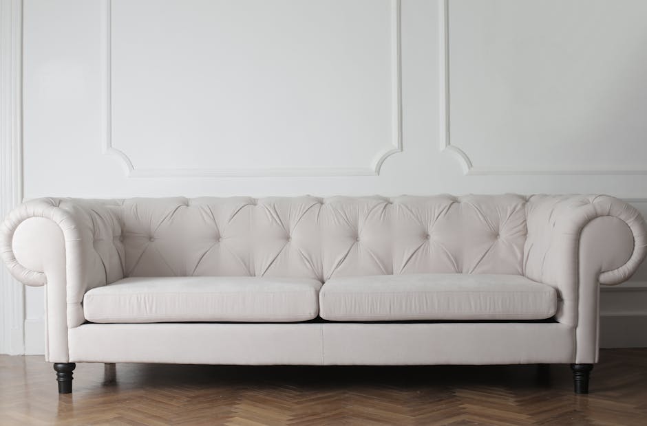 Close-up view of a beige fabric sofa in a living room, featuring neatly arranged teal and beige cushions. The surface of the sofa appears clean and well-maintained, with no visible dust or stains. In
